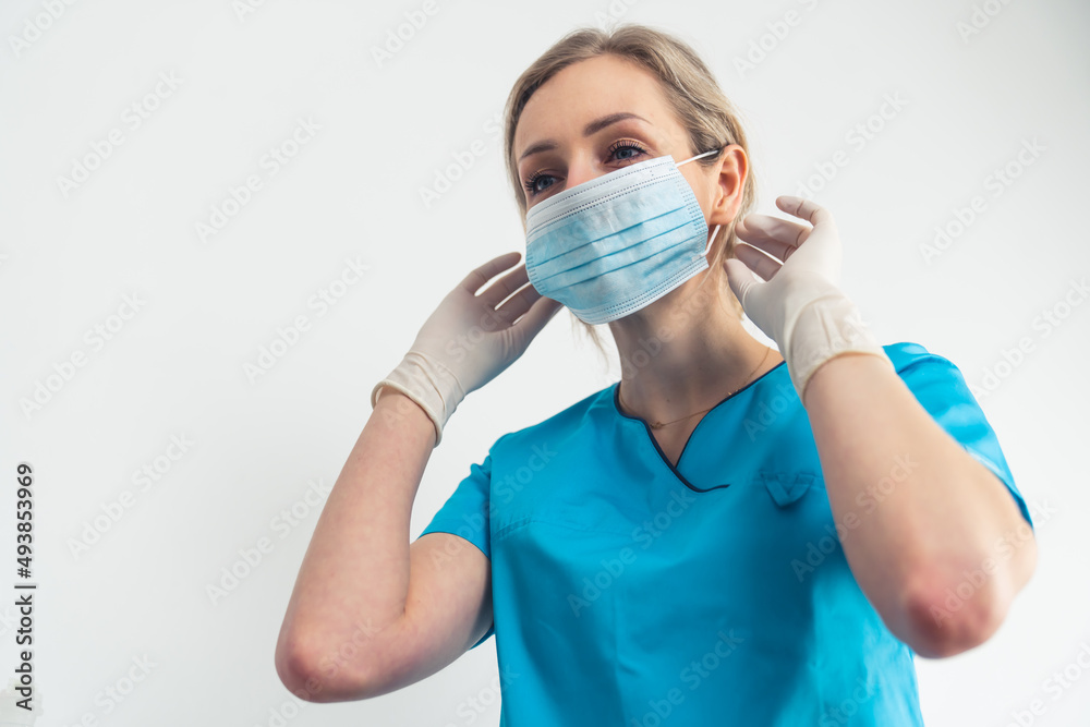 Young blonde caregiver shows how to safely remove surgical mask. High quality photo Young blonde caregiver shows how to safely remove surgical mask. High quality photo