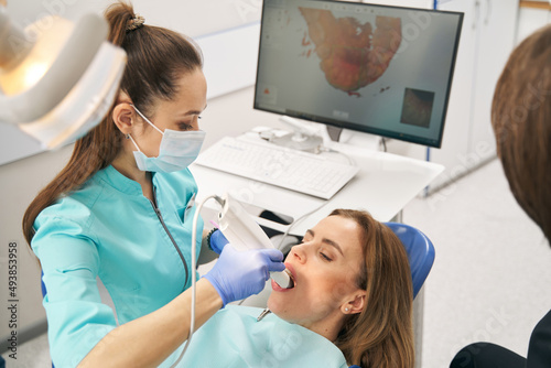 Dentist scanning woman teeth with dental intraoral 3D scanner