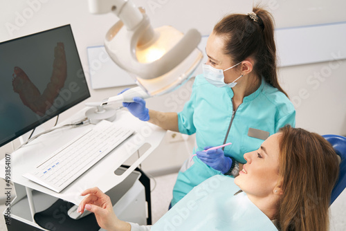 Dentist discussing results of dental 3D scanning with woman in clinic