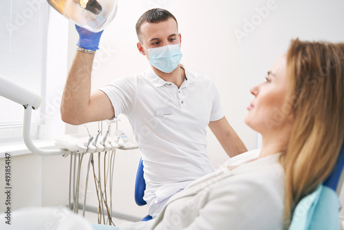 Male dentist sitting next to patient in dental clinic