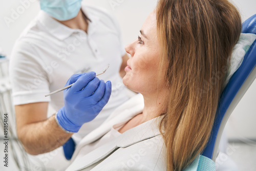 Male dentist examining woman teeth with dental tool