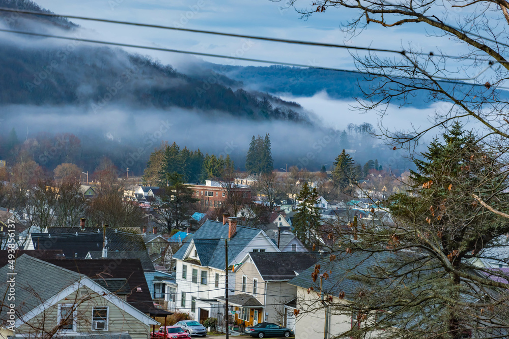 Fototapeta premium Bradford PA mountain USA town with morning fog rising above the mountains, landscape nature composed with classic building architecture.