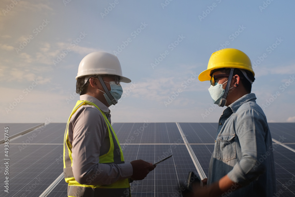 Engineer working with workers working as a team against the backdrop of a solar panel, a renewable energy concept. Engineer working with workers working as a team against the backdrop of a solar panel, a renewable energy concept.