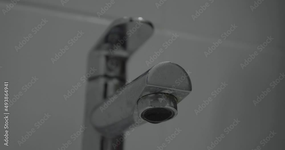 dripping water from the chrome faucet in the white bathroom. world water day dripping water from the chrome faucet in the white bathroom. world water day