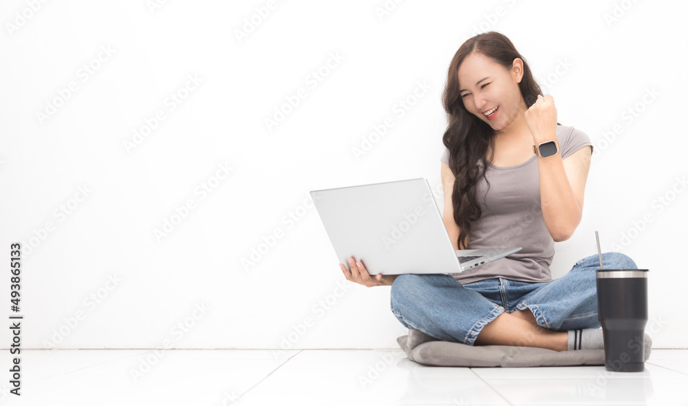Beautiful Asian woman wearing grey casual shirt using laptop on white background and copy space. Cute Asian woman sitting on the floor room relaxing and excited something for work from home concept Beautiful Asian woman wearing grey casual shirt using laptop on white background and copy space. Cute Asian woman sitting on the floor room relaxing and excited something for work from home concept