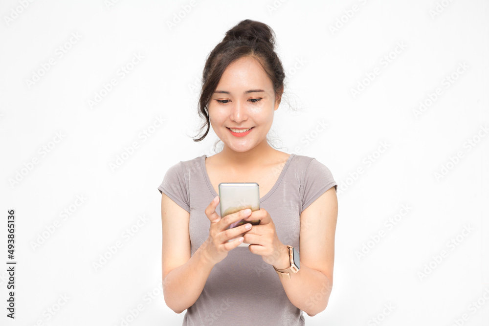 Beautiful Asian woman wearing grey casual shirt holding smartphone on white background and copy space. Cute Asian woman is smiling and chatting about something for social media concept Beautiful Asian woman wearing grey casual shirt holding smartphone on white background and copy space. Cute Asian woman is smiling and chatting about something for social media concept