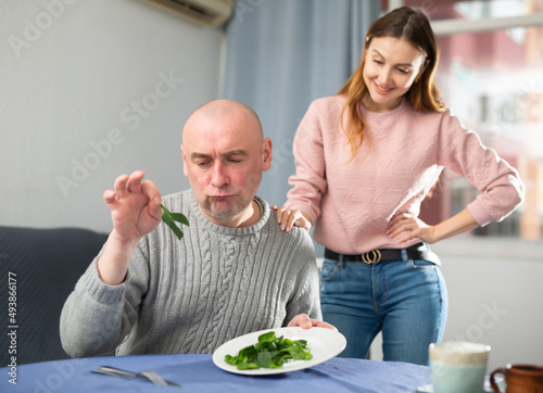 Woman serving salad for her displeased husband. Wife making dinner for husband.