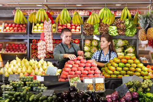 Portrait of male and female shop assistants working responsibly in fruit and vegetable shop photo