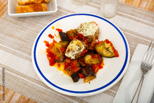 Stewed eggplant with vegetables, meatballs and cheese served on plate