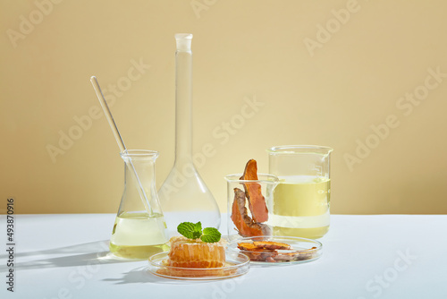 A front view of honey and turmeric extract with laboratory equipment in beige background for advertising