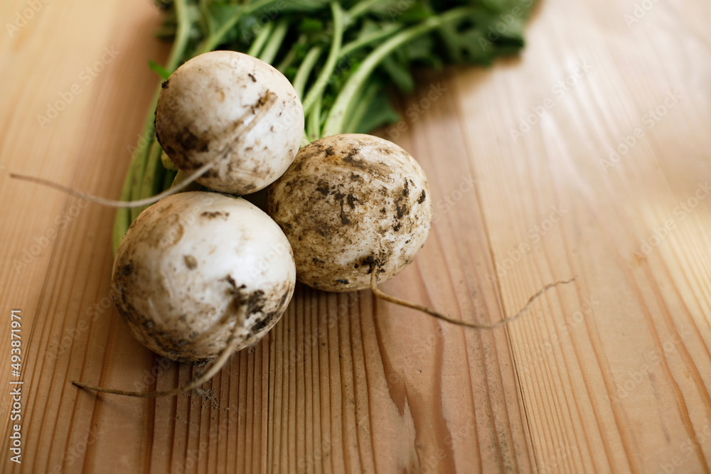 Fresh white turnip greens sitting on the wooden table. Beautiful soft sunlight. Fresh white turnip greens sitting on the wooden table. Beautiful soft sunlight.