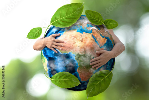 environmental concept on earth day hands hugging the earth with green leaves
