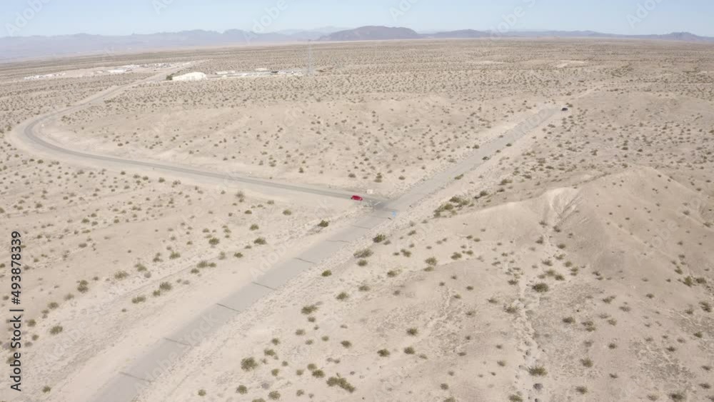 Aerial view following a red car driving through the desert Aerial view following a red car driving through the desert
