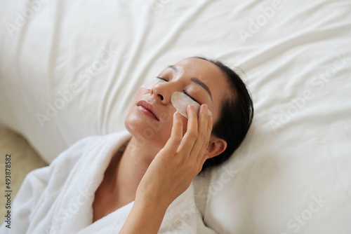 Young woman applying undereye patches to get rid of morning puffiness