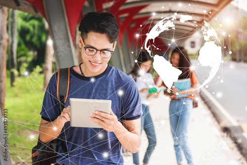 Male student reads on tablet computer at campus. There are groups of girl riends behind, Education concept photo