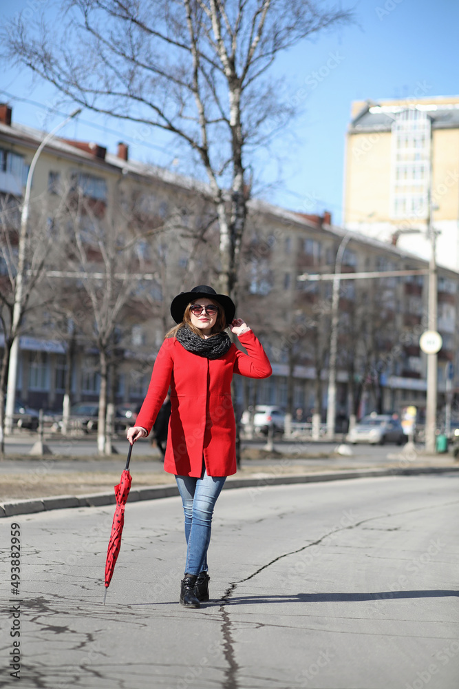 Pretty girl on a walk in red coat in the city
