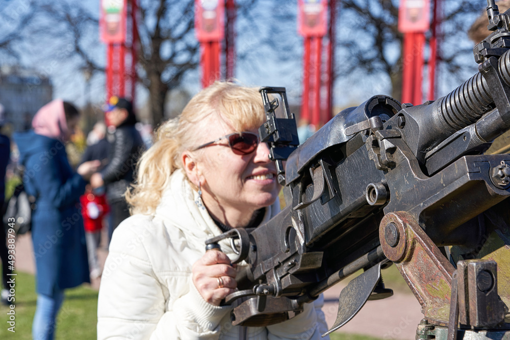 blonde woman in dark glasses shoots an anti-aircraft machine gun aiming upwards blonde woman in dark glasses shoots an anti-aircraft machine gun aiming upwards