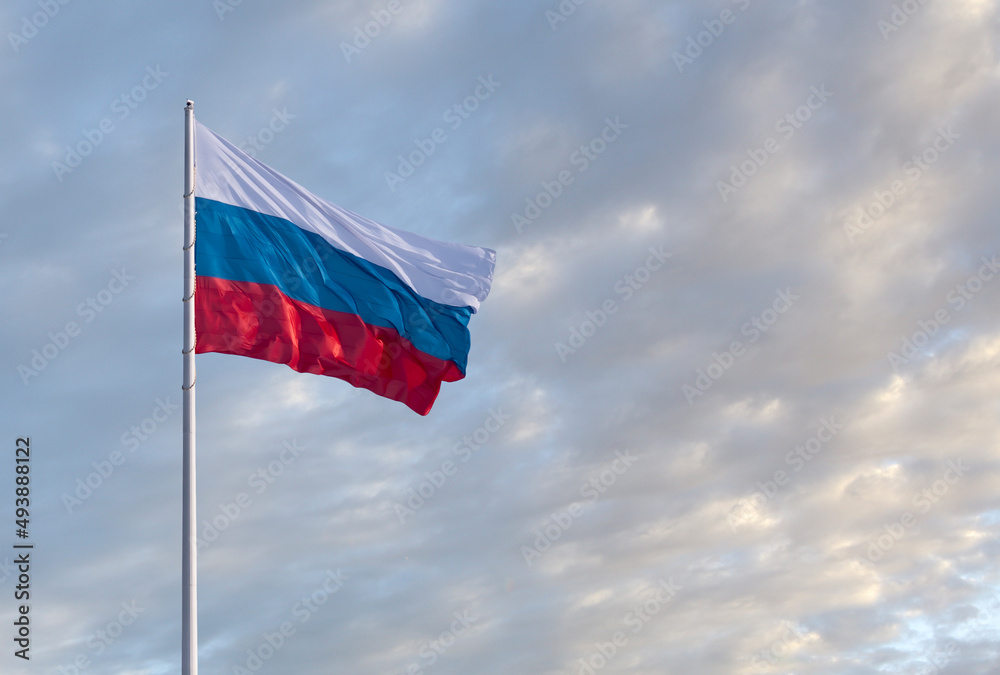 Waving Russian flag against a blue sky with clouds and empty space for text. Room for text. Waving Russian flag against a blue sky with clouds and empty space for text. Room for text.
