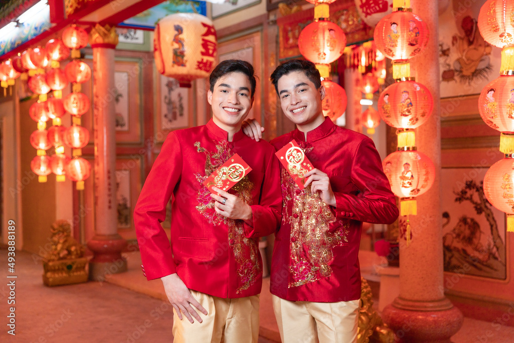 Attractive chinese man in traditional clothes showing angpao on his hands. Happy Chinese New Year