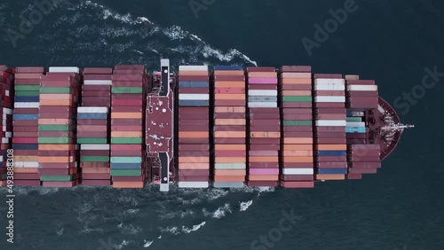 Aerial top view of a loaded container cargo vessel traveling over ocean.