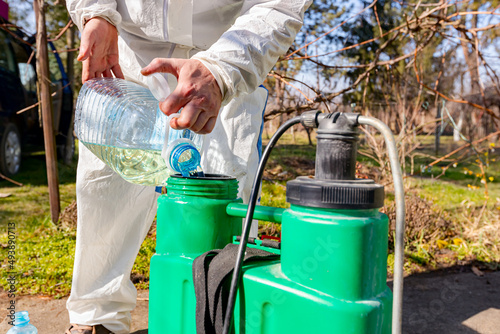 Gardener is blending substance with water in proper scale for sprinkles fruit trees