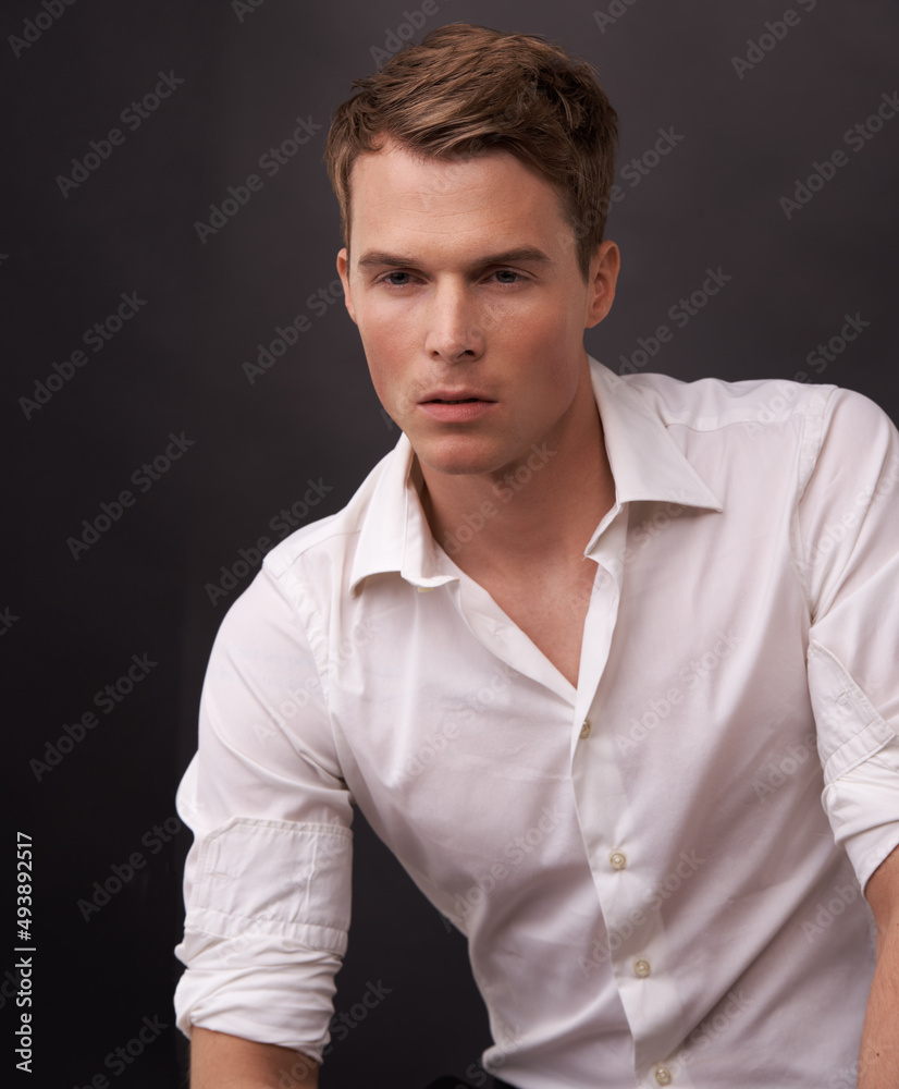 Handsome and reserved. A handsome young man in a white shirt against a black background. Handsome and reserved. A handsome young man in a white shirt against a black background.