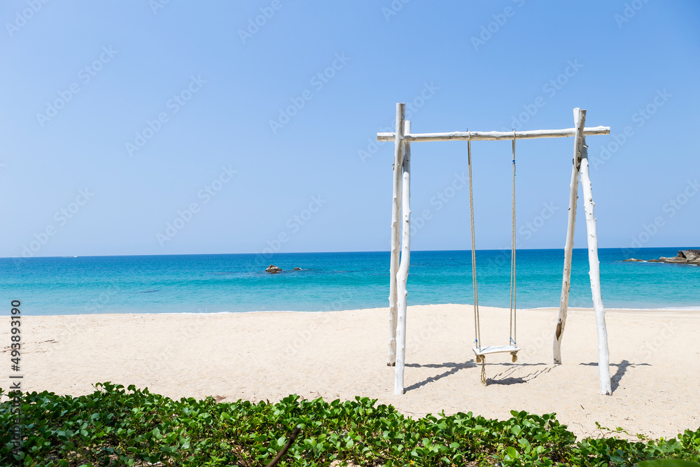 Wooden swing on beautiful sand beach in South of Thailand, summer holiday and vacation destination, tropical beach, summer outdoor day light, relax by the sea Wooden swing on beautiful sand beach in South of Thailand, summer holiday and vacation destination, tropical beach, summer outdoor day light, relax by the sea