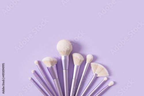 Professional makeup tools brushes on a pastel violet background. Set of glamour makeup brushes. Magazines, social media. Visagist tools. Top view, copy space. Creative flat lay. Cosmetics products