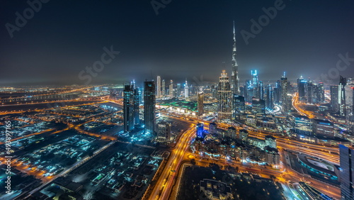 Aerial panorama of tallest towers in Dubai Downtown skyline and highway night timelapse.