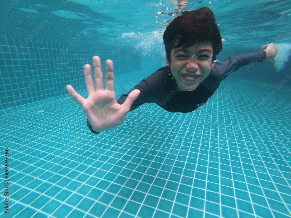 Little boy having fun playing underwater in the pool happy smile