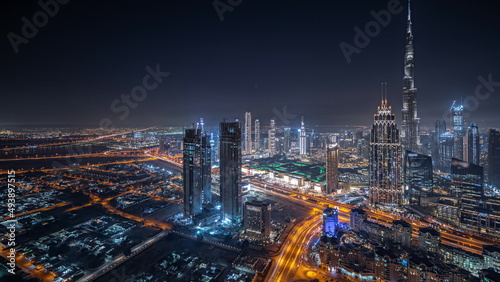 Panorama showing aerial view of tallest towers in Dubai Downtown skyline and highway night timelapse.