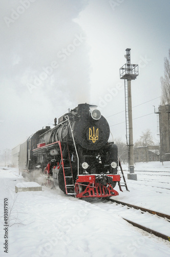 Vintage black steam locomotive. Old Soviet steam train in the depot. Space for text. Background with a steam train in the wintertime. New Year express.