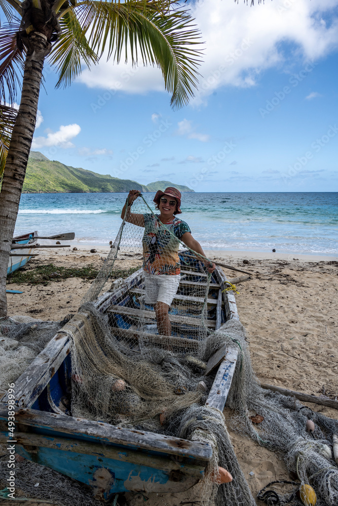 Φωτογραφία woman tourist near a fishing boat with a net on a sandy beach in the Dominican R