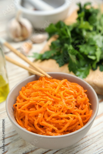 Delicious Korean carrot salad in bowl on white wooden table