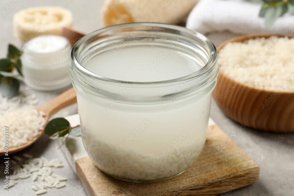Glass jar with rice soaked in water on light grey table Glass jar with rice soaked in water on light grey table