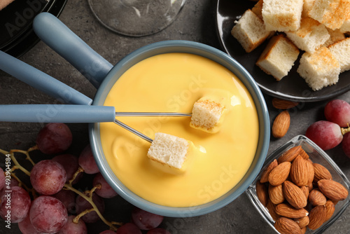 Flat lay composition with pot of tasty cheese fondue on grey table
