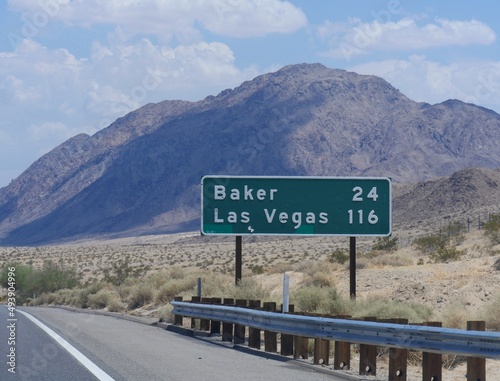 Medium close up of a roadside sign with distances to Baker and Las Vegas along Interstate 15 in California.