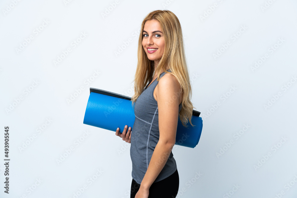 Young sport woman going to yoga classes while holding a mat over isolated white background smiling a lot Young sport woman going to yoga classes while holding a mat over isolated white background smiling a lot