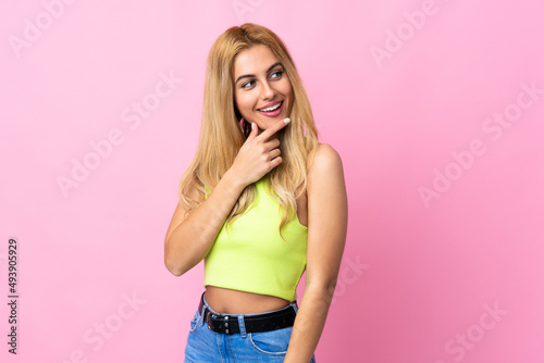 Young Uruguayan blonde woman over isolated pink background looking up while smiling © luismolinero