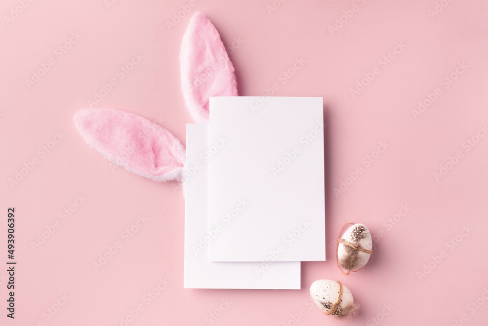 Easter mockup with decorative rabbit ears and eggs, poster on pink background Easter mockup with decorative rabbit ears and eggs, poster on pink background
