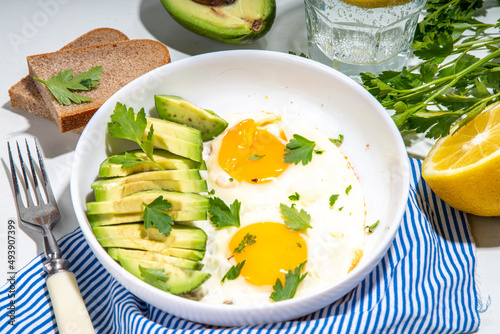 Healthy breakfast. Keto, balanced diet. Fried eggs with sliced avocado and toasts on white table background