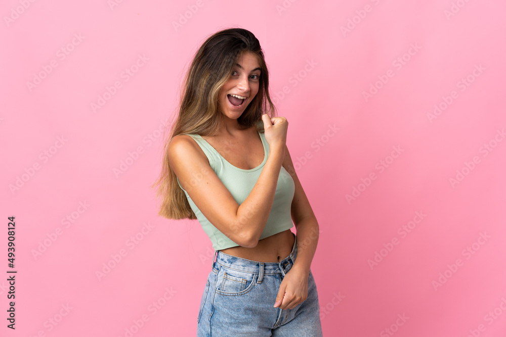 Young caucasian woman isolated on pink background celebrating a victory