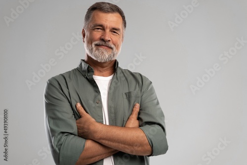 Portrait of smiling mature man standing on white background photo