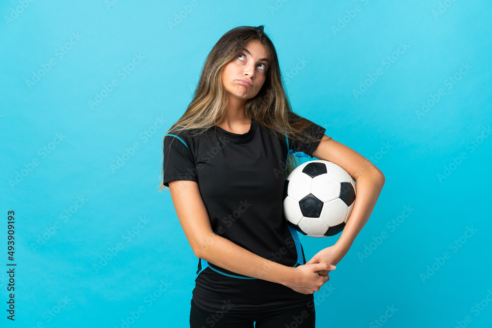 Young football player woman isolated on blue background and looking up Young football player woman isolated on blue background and looking up