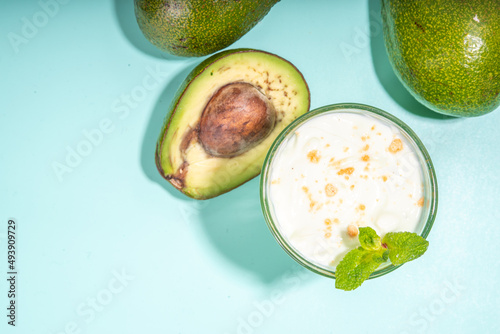 Healthy green snack drink. Vegan non-dairy, keto diet cocktail. One Glass with Avocado Milk Shake or Smoothie and fresh avocado on turquoise table background