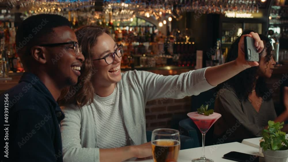 Diverse group of friends taking selfies in restaurant together Diverse group of friends taking selfies in restaurant together