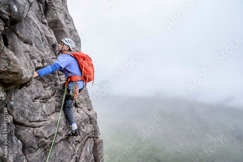 Man wearing helmet climbing rocky mountain