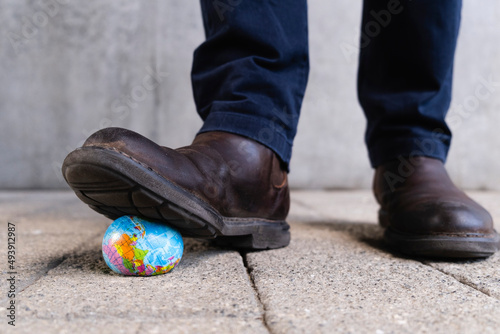 Man pressing toy globe in front of gray wall