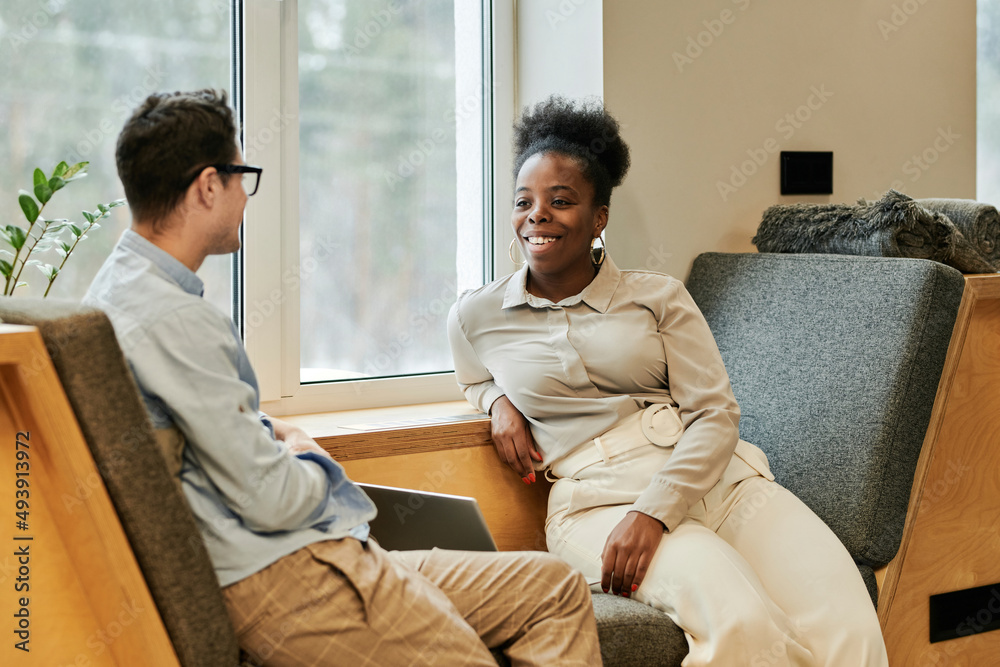 Happy business colleagues talking to each other at office Happy business colleagues talking to each other at office