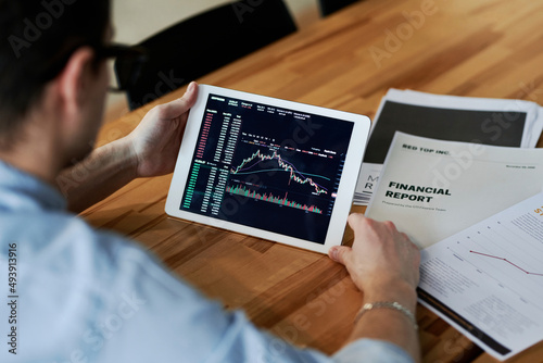 Businessman reviewing cryptocurrency data on tablet PC at office